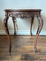 Front view of entire table showing carved apron and legs against wall