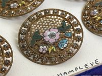 Close-up of single button showing enamel floral design and lattice background