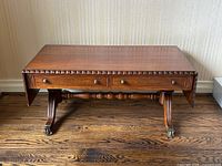 Front view with both drop leaves down, showing drawers and apron carving