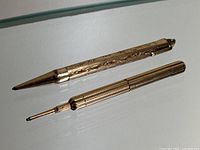 Two gold-filled mechanical pencils side by side on white surface