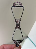 Full view of unfolded lorgnette and attached chain necklace on white background