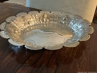 Front view of oval dish showing scalloped edge and floral repousse pattern