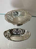 Overview of both pedestal bowl and oval dish on glass surface