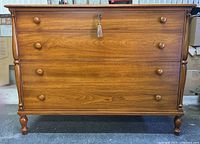 Front view showing four drawers, round knobs, and central lock with tassel