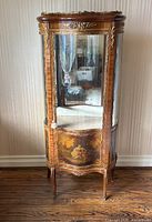 Front view of cabinet showing painted panel, glass door and ormolu mounts