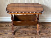 Front view of walnut end table showing top, apron carving, magazine rack and cabriole legs