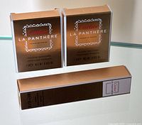 Two Cartier La Panthère 1g perfumed powders in gold-tone packaging plus one 9ml Eau de Parfum spray boxed in gold-tone packaging, displayed on reflective surface.