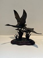 Front view of bronze geese in flight on wooden base
