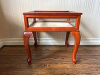 Front view of glass and wood display table with upholstered display area inside.