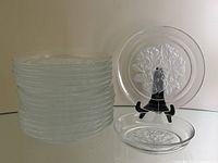 Stack of 16 clear crystal plates with one plate displayed showing floral design