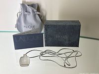 Necklace, box, pouch and papers arranged on glass surface
