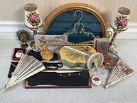 Overview of lot showing gold fan frame, lamps, sign, trinket dishes, fans, compacts, pouches, purse hook, lipstick case, gloves