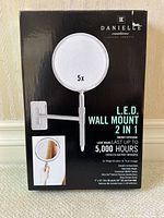 Front view of product box in English showing 5x magnifying LED wall mount 2-in-1 mirror by Danielle Creations, with features and measurements.