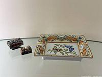 Photo showing the rectangular Limoges porcelain ashtray decorated with colorful butterflies and scenic landscape, alongside two decorative porcelain matchbox holders.