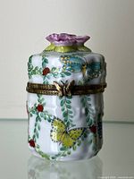 Frontal view of closed porcelain holder showing painted motifs and overall form