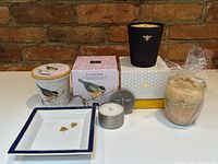 All items displayed together: four candles and porcelain tray against brick background