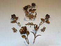 All seven metal Florentine floral picture hooks arranged on a white surface showing varying floral designs and hooks.