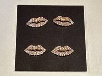 Set of four lip-shaped rhinestone buttons displayed on black card background, showing all buttons together for scale and presentation.