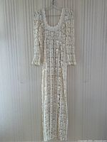Full front view of cream crochet maxi dress hanging on hanger.