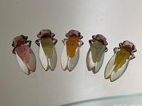Full view of five vintage plastic cicada insect buttons in a row showing colors and details.