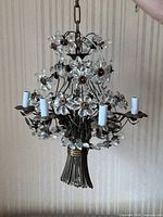 Full view of chandelier hanging by chain showing metal frame, six light sockets, and glass flower accents.