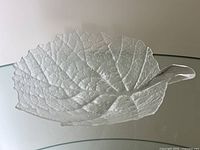 Top and side view of the clear glass leaf-shaped bowl showing detailed vein texture and sculpted stem handle.