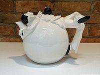 Front view of vintage Pierrot clown ceramic teapot showing the round body and handle leg.