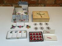 Full lot overview showing porcelain place card holders, metal starburst holders, lucite holders with red flowers, and Aloha place cards.