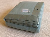 Folded blanket on carpet showing overall appearance and satin trim