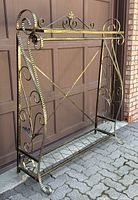 Full left-angle view of coat rack showing overall frame shape, scroll details and bottom shelf