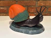 Full view of snail lamp on white surface against brick background