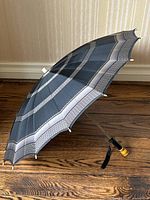 Side view of vintage umbrella showing patterned canopy and Bakelite handle.