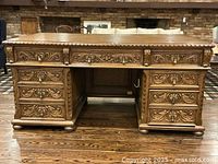 Front view of full desk showing carved apron, central lion head panel, three drawers per pedestal