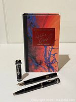 Box upright with booklet behind uncapped fountain pen and capped ballpoint pen in front