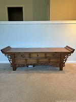 Full frontal view of the wooden decorative bench showing overall structure, drawers, and curved end details.