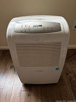 Front view of white Commercial Cool dehumidifier showing control panel with digital display and vent grille.