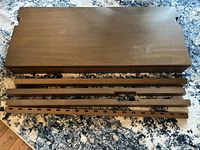 Disassembled desk parts including the flat tabletop and supporting rails laid out on a carpet.