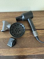 Hair dryer main body and three attachments laid out on wooden surface