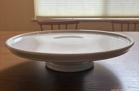 Side angle view of white ceramic cake stand showing glossy surface and pedestal base