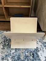 Front view of the wooden magazine rack showing one large panel and the base with screws.