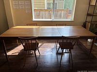 Side view of extended table with leaf inserted and surrounding chairs