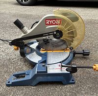 Side view of the Ryobi corded miter saw showing saw blade, safety guard, brand logo, and base with miter angle markings.