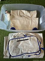 Folded beige inflatable boat parts and storage bags inside clear plastic bin.