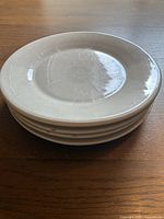 Stack of four terracotta dinner plates showing the light beige glazed top finish and thickness of the plates.