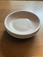 Stack of three terracotta soup plates showing the top curved shallow bowl shape and crackle glaze finish.