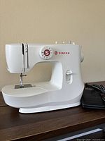 Front view of white Singer mini sewing machine with stitch selection dial and foot pedal