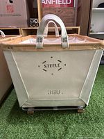 Front view of the canvas carry basket showing the 'STEELE 380' marking, vegetable-tanned leather rim, canvas handles, and sturdy construction.