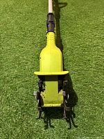 Close-up of the cultivator's forward-rotating metal tines and yellow motor housing at the base.