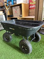 Angled view of black plastic wagon showing four shock-absorbing pneumatic tires and construction details