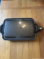 Top view of the rectangular Zojirushi electric hot plate showing smooth black nonstick cooking surface, black frame, and side handles.